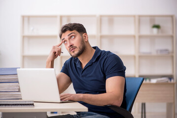 Young male employee sitting at workplace