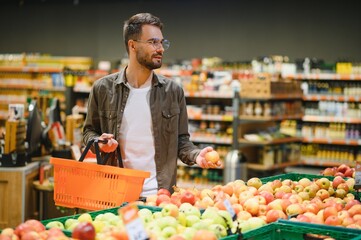 Man buying vegetables and fruit in reusable bag in grocery store, zero waste concept