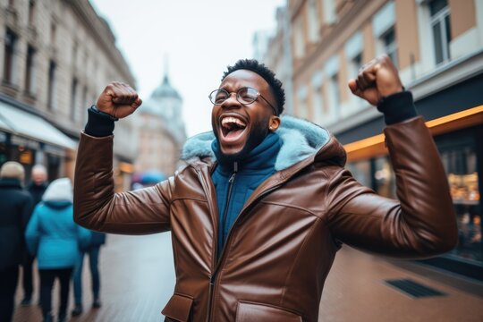 Portrait of overjoyed bearded man standing with excited expression, raising fists, screaming, shouting yeah, celebrating his victory, success. 