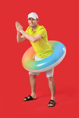 Young man with inflatable ring on red background