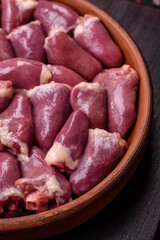 Fresh raw chicken or turkey hearts in a ceramic plate with salt, spices and herbs