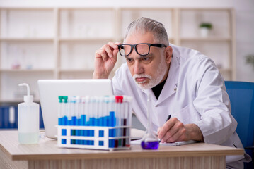 Old male chemist working at the lab