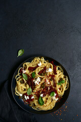 Pasta bavette with dried tomatoes, kapers and ricotta. Top view with copy space.