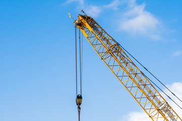 Naklejka premium A yellow crane at a construction site during a sunny day