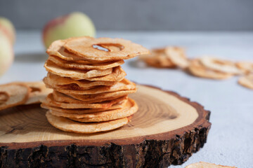 Apple chips, dried apple slices on a wooden stand. Organic apple chips on a light background. dehydrated apple chips.