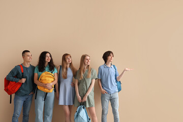 Group of students with backpacks near beige wall