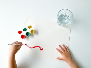 small child draws with paints and brush on white table. fathers day