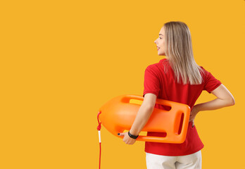 Female lifeguard with rescue buoy on yellow background, back view