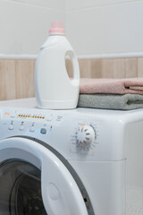 Washing gel liquid laundry detergent and fabric softener on washing machine, clean towels on washing machine. High quality photo