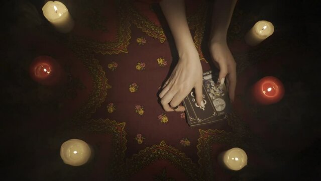 Top view of a fan of tarot cards laying on the table with one card open, female hands taking off the layout from the desk. HDR BT2020 HLG Material.