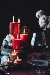 Rustic table decor for Christmas or New Year family dinner. Centrepiece with red candle, dry orange, cone, cinnamon, anise. Zero waste eco-friendly home. Cozy atmosphere, dark background. Close up
