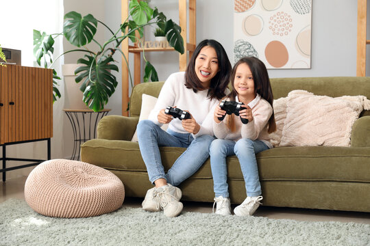 Asian Mother With Her Little Daughter Playing Video Game At Home