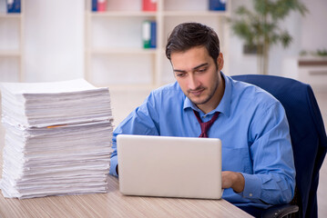 Young male employee and too much work in the office