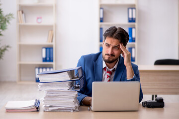Naklejka premium Young male employee and too much work in the office