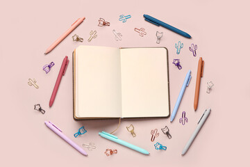 Blank notebook with school stationery on light pink background