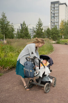 Woman putting baby to sleep in buggy at park during summer