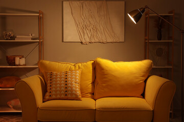 Interior of living room with sofa and glowing lamp at night