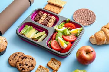 Lunchbox with delicious food and thermos on blue background