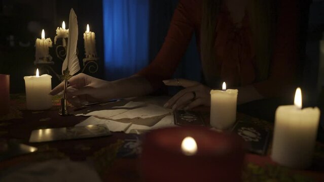 Close up shot of woman sitting on the table with many candles and tarot cards laying around. HDR BT2020 HLG Material.