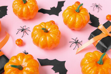 Composition with gift box, pumpkins, paper bats and spiders on pink background, closeup. Halloween celebration concept