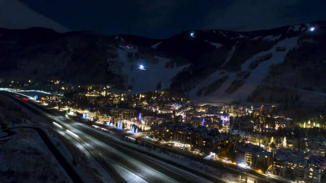 Aerial Forward Shot Of Cars Moving On Road By Illuminated Buildings At Night, Drone Over City In Winter - Vail, Colorado
