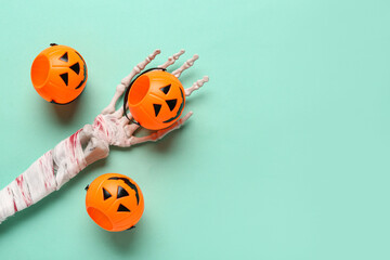 Skeleton hand with pumpkins for Halloween celebration on turquoise background
