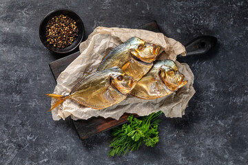 dried fish on a wooden board on a gray background with spices