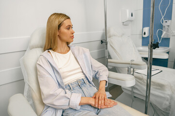 Woman sitting in armchair while waiting for IV infusion in hospital. High quality photo