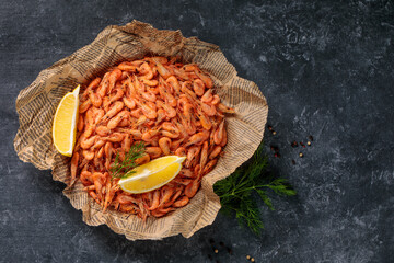 Small shrimps cooked in a bowl with lemon, garlic on a gray background