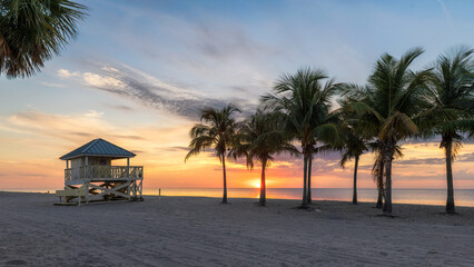Tropical beach at Sunset with palm trees and lifeguard tower in Miami Beach, Florida.