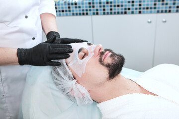 Care for man's face in beauty salon.Man with clay mask on his face.Men's cosmetology.