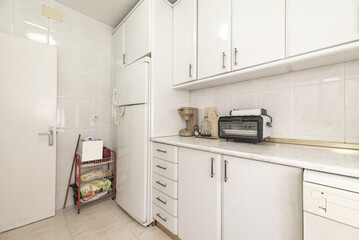 Used kitchen furnished with white furniture and integrated appliances of the same color
