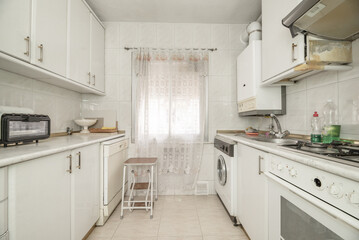 Small old kitchen furnished with white wooden cabinets on both sides