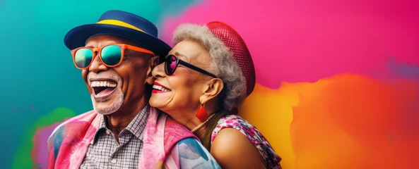 Foto op Canvas Happy elderly couple in love, hugging and smiling together on a colorful background. Active senior lifestyle concept : Sunset of life in colors. © mozZz