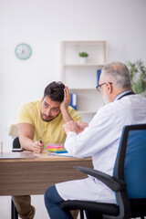 Obraz premium Young male patient visiting old male doctor