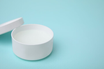 Jar of petroleum jelly on light blue background, space for text