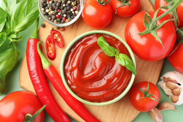 Bowl of tasty ketchup and ingredients on green table, flat lay