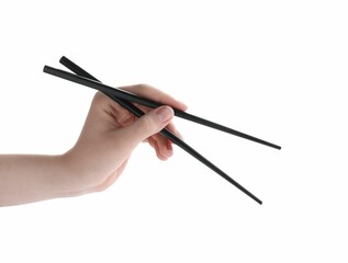 Woman holding pair of black chopsticks on white background, closeup