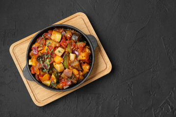 Dish with tasty ratatouille on black table, top view. Space for text