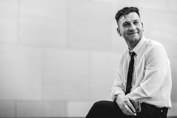 Urban business lifestyle: modern and young professional with white shirt and black tie using a phone in business district (in black and white)