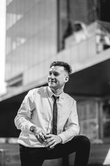 Urban business lifestyle: modern and young professional with white shirt and black tie holding eco-friendly coffee cup in business district (in black and white)