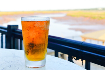 A frosted clear pint glass contains a sour craft beer from a microbrewery. The local beer is on a...