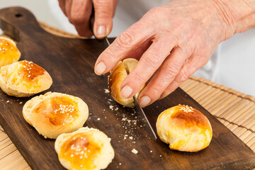 Cutting small bread buns for mini burgers. Step by step preparation of mini burgers. Homemade mini burgers for children or appetizers. Small hamburgers.