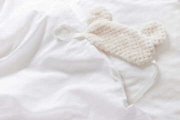 Sleep mask from soft nice fur on bed with white pillow and blankets bedclothes. Cozy life style...