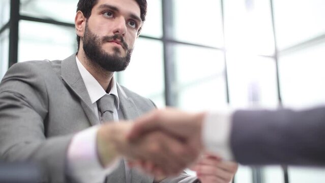Close up of business greeting handshake over office work table.
