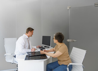 Male doctor explaining ultrasound examination result for sick female patient in hospital office