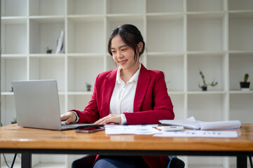 A beautiful Asian businesswoman working on her business project on laptop at her desk