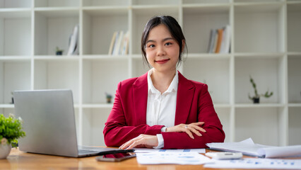A portrait of a beautiful Asian businesswoman smiling at the camera while sitting at her desk