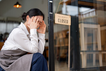 A crying and upset Asian female coffee shop owner feeling sad to close her business.
