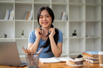 A pretty Asian female college student sits at her study table at home.